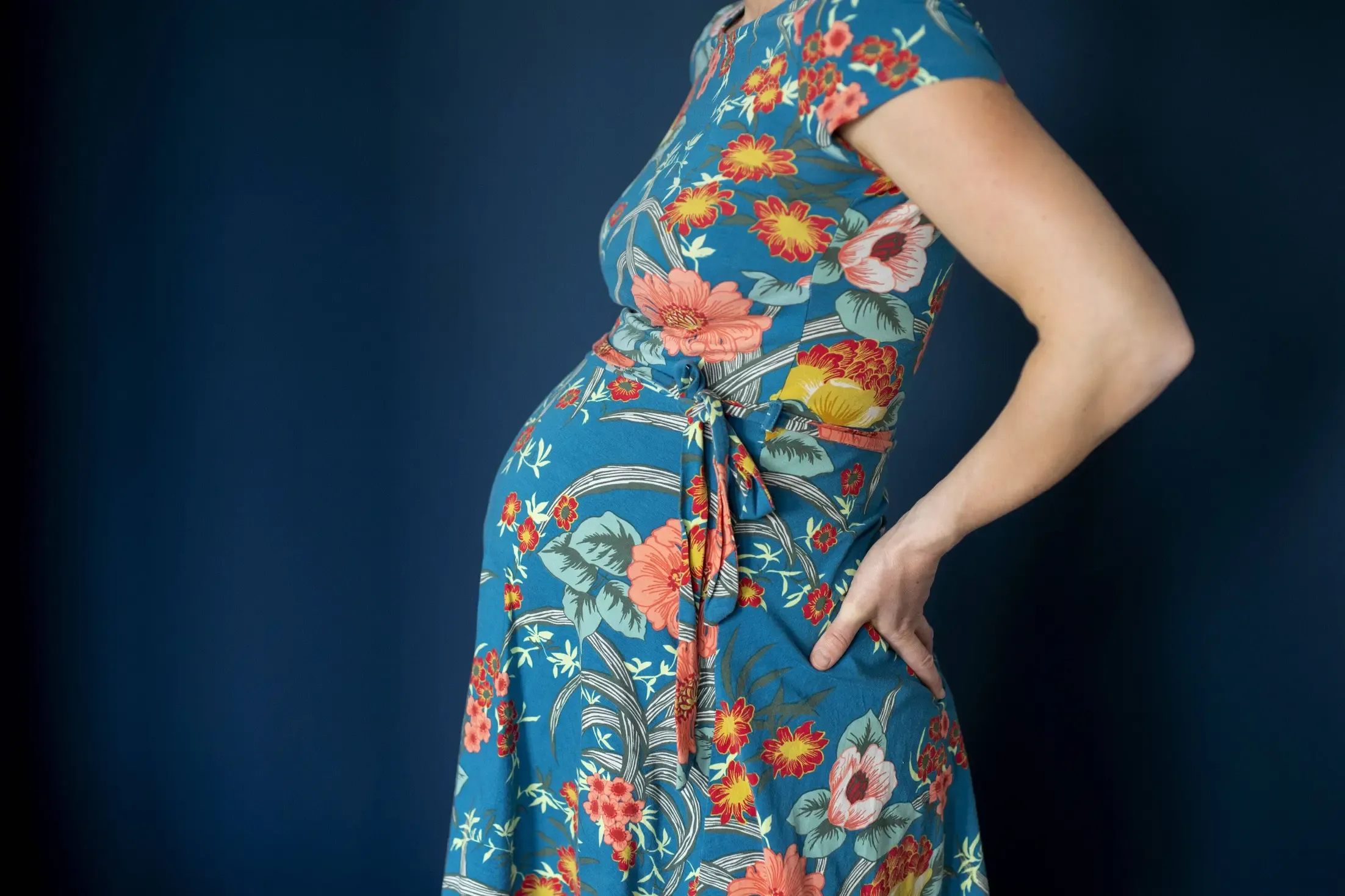 Bild einer schwangeren Frau in einem Kleid mit Blumenmuster