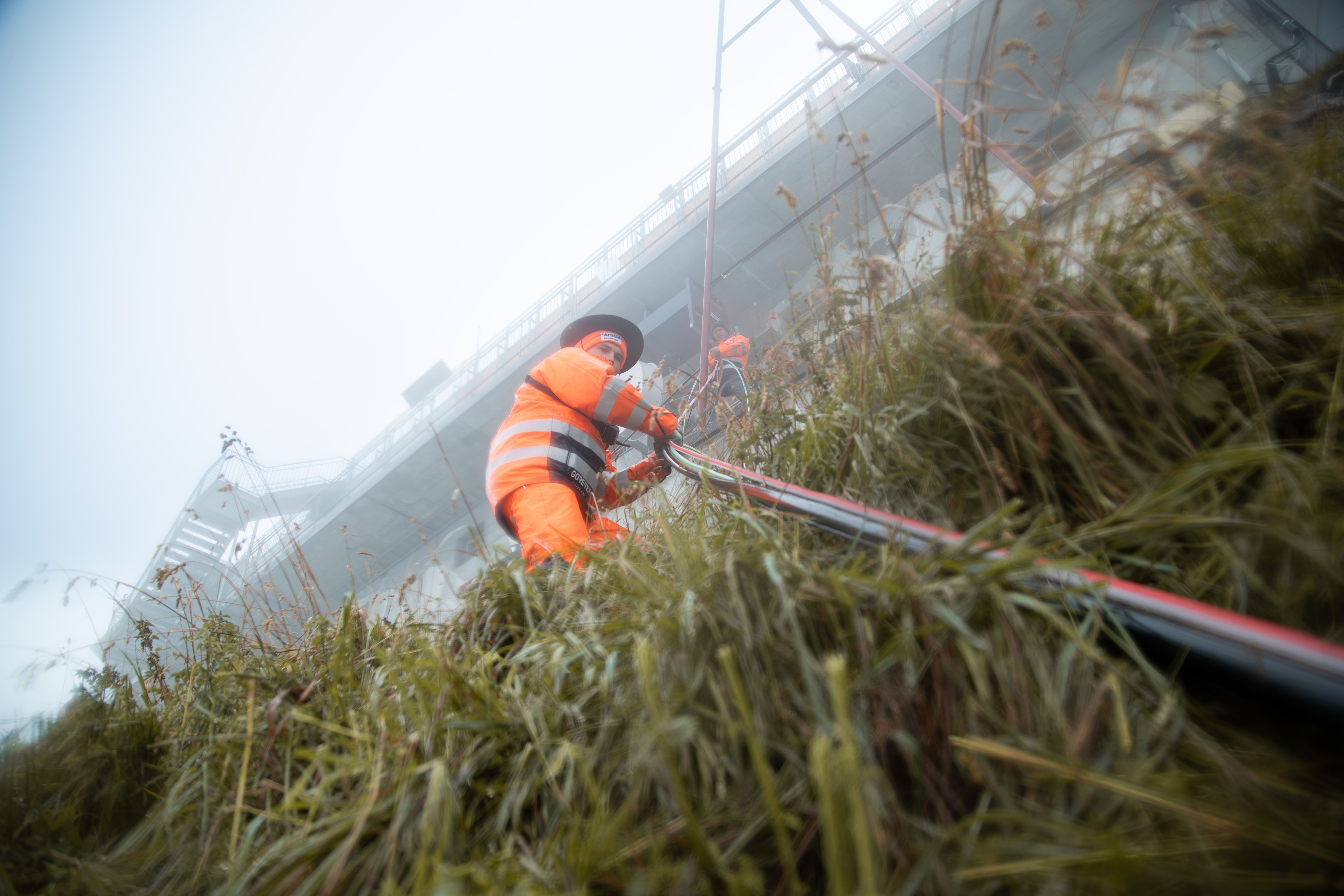 Ein Mitarbeiter der Arnold AG zieht an einem steilen Hang Leitungen ein