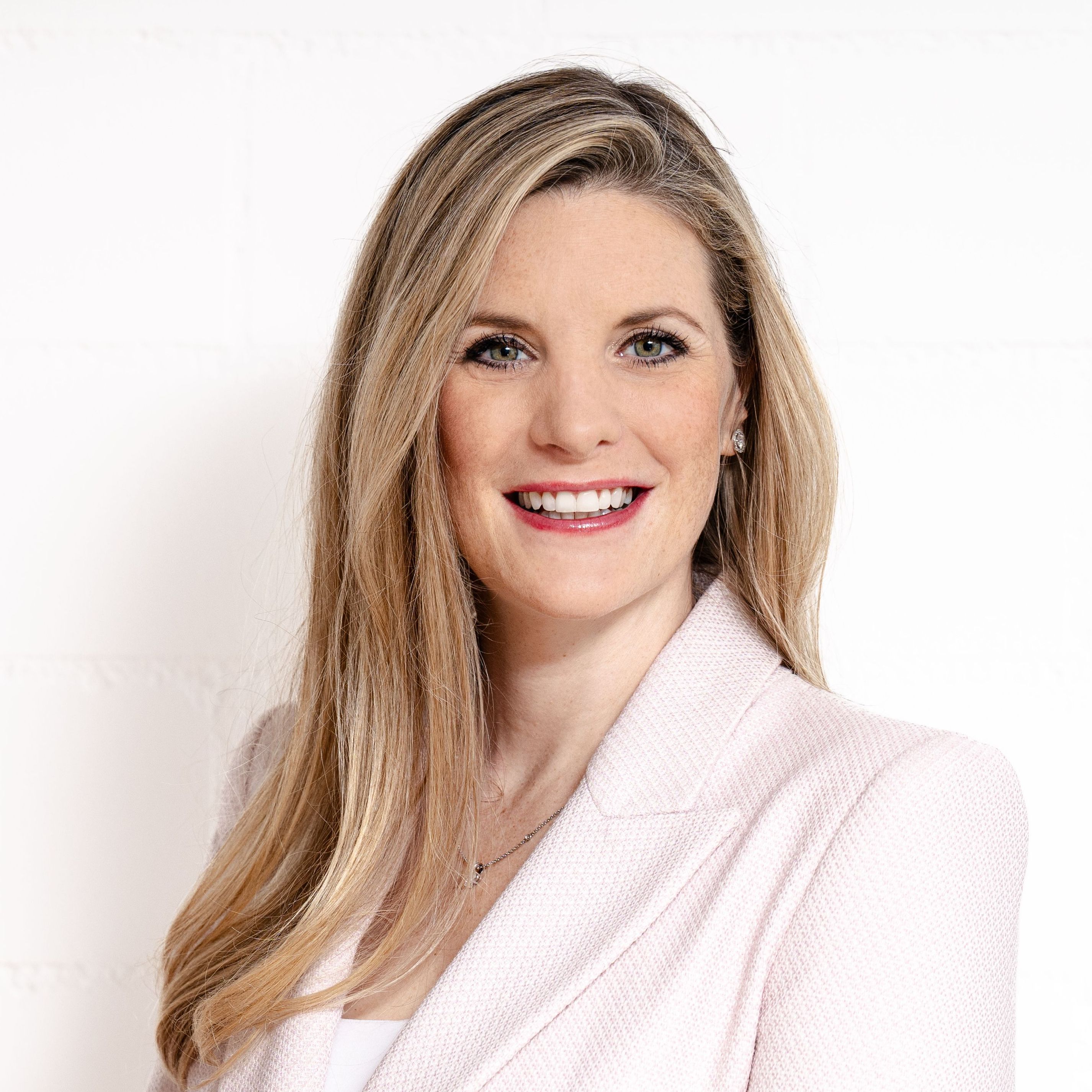 Nathalie Agosti in hellem Blazer, lächelnd vor weisser Wand; steht für soziale Nachhaltigkeit und mentale Gesundheit als Führungsaufgabe in Unternehmen.