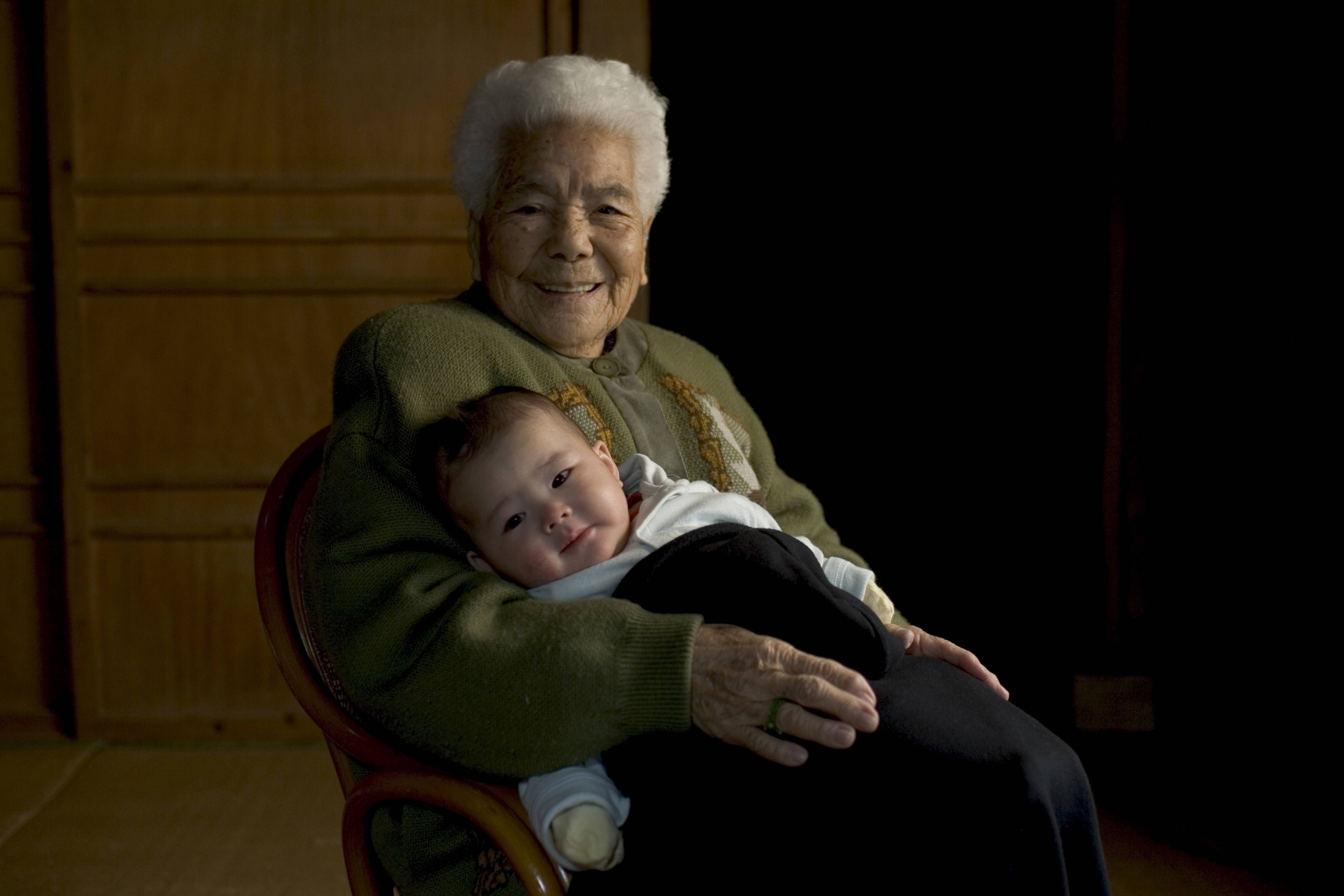 Die 102-jährige Kamada Nakazato aus Okinawa hält ihre Ururenkelin auf dem Schoss.