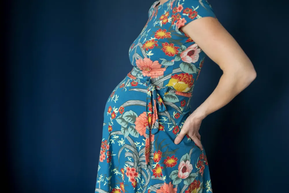 Bild einer schwangeren Frau in einem Kleid mit Blumenmuster