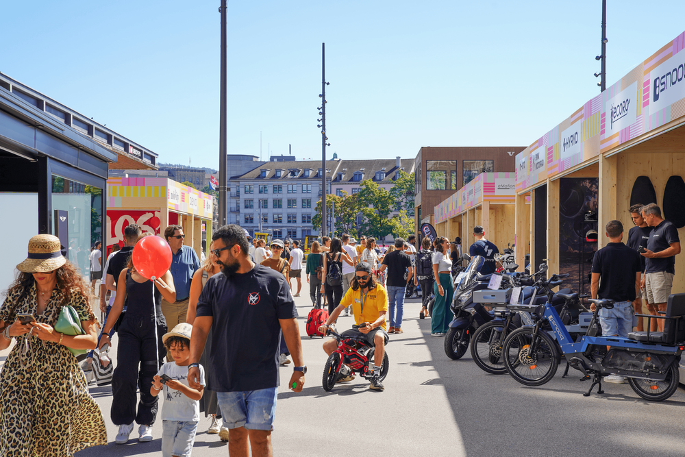 Menschen gehen bei schönem Wetter durch das Messegelände der E-nova 2024