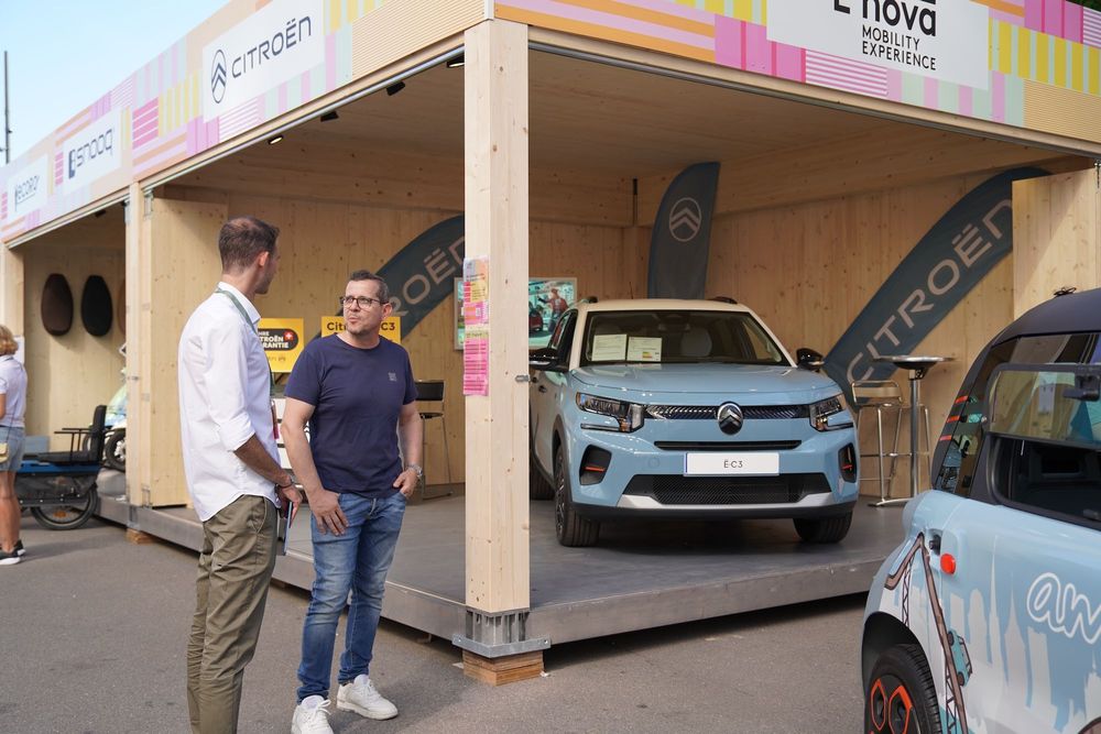 Zwei Männer stehen an der E-nova 2024 vor einem ausgestellten E-Auto