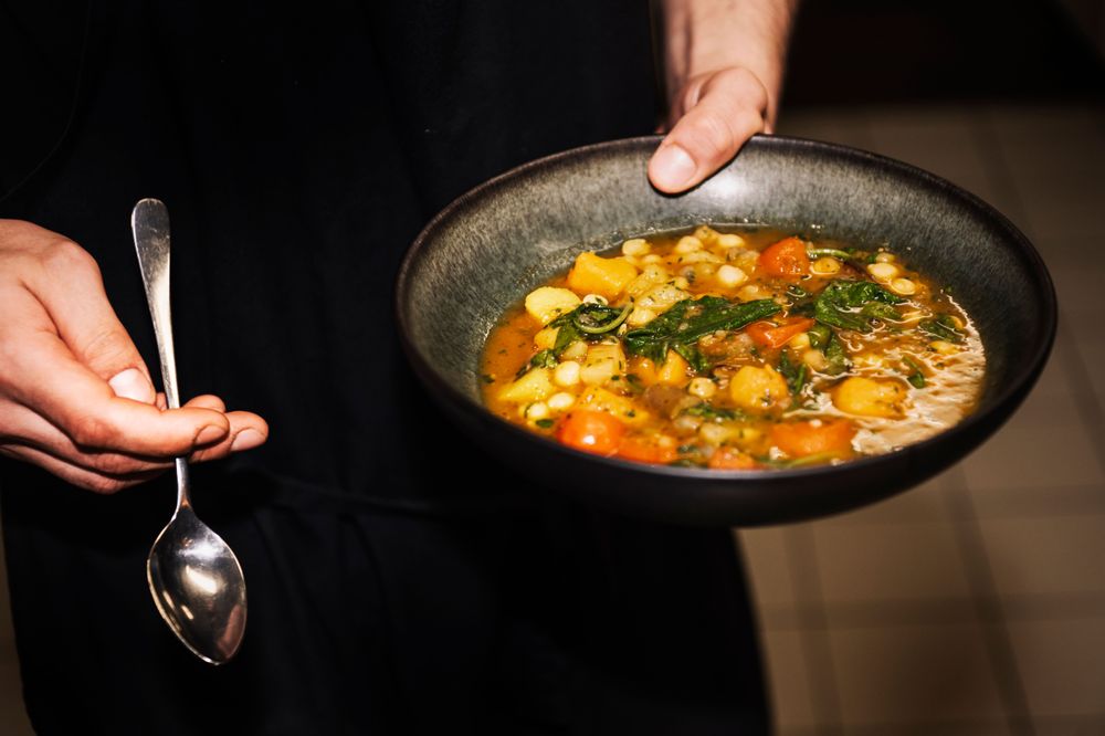 Une personne tient une assiette avec un plat végétarien dans la main