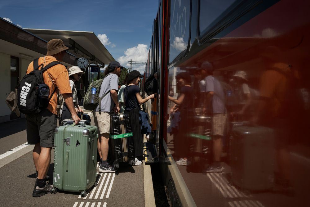 Eine Gruppe asiatischer Touristen steigt mit ihren Koffern am Bahnhof in Lungern in einen Zug ein. 