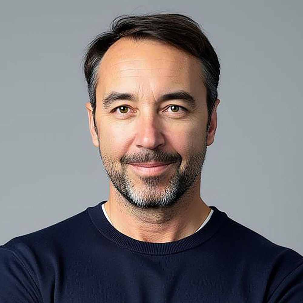 Oliver Brunschwiler in top scuro davanti a uno sfondo grigio in un ritratto