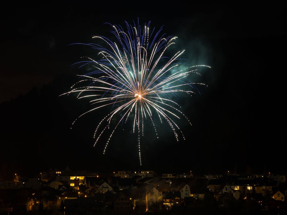 Ein Feuerwerk am Nachthimmel über einem Dorf 