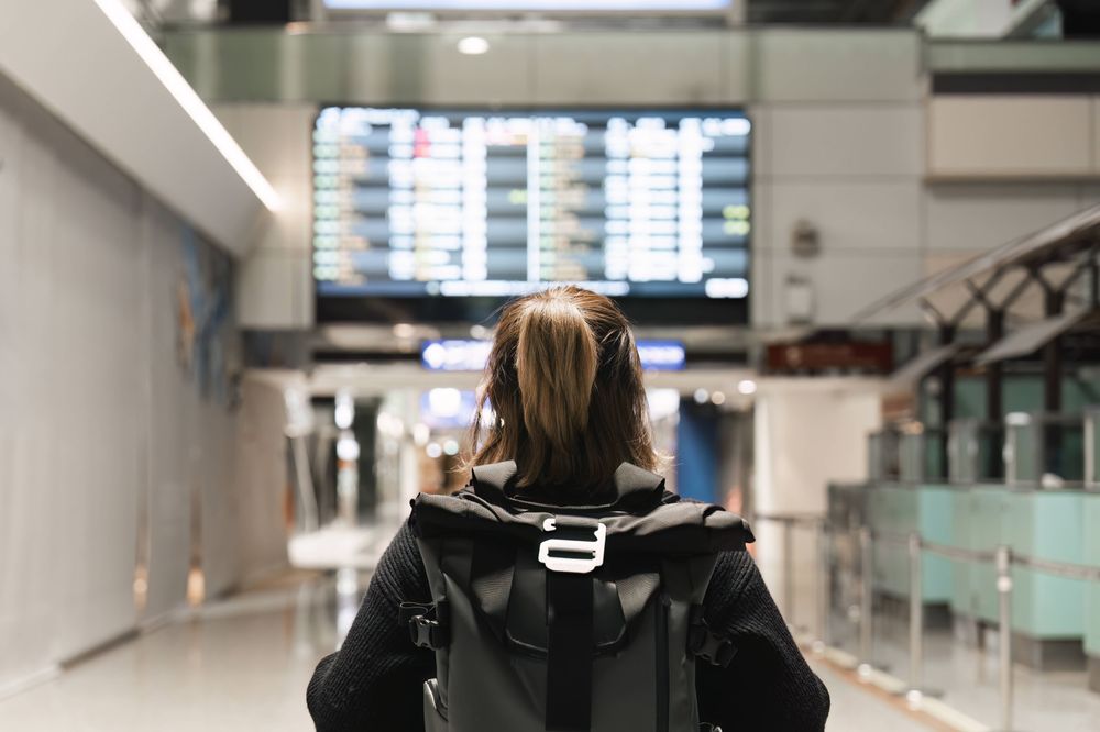 Eine Frau steht am Flughafen vor einer grossen Anzeigetafel