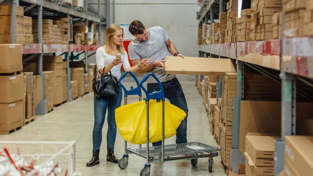 Ein Paar lädt in der Selbstbedienungshalle von Ikea ein Paket auf ihren Einkaufswagen
