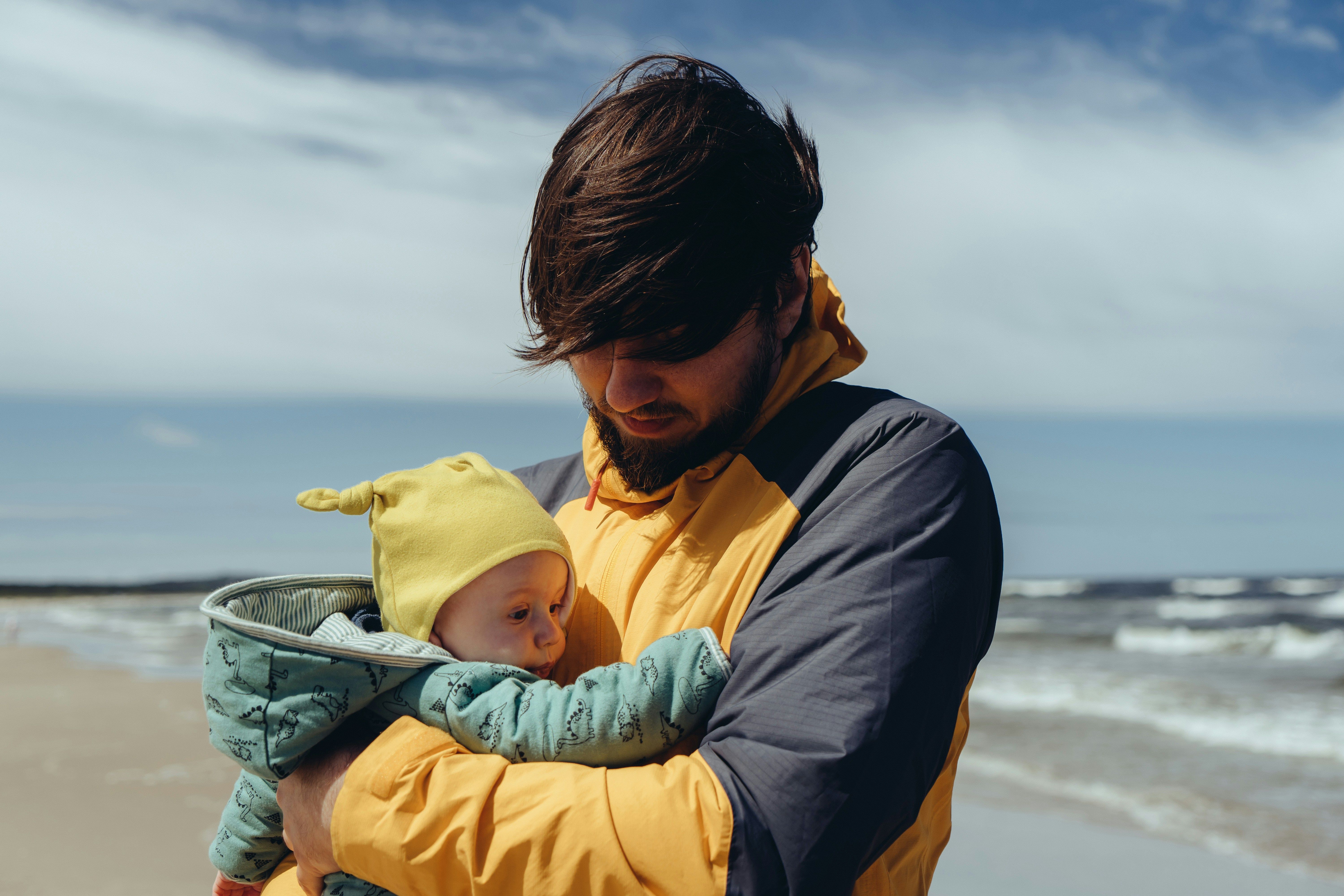 https://unsplash.com/de/fotos/mann-in-schwarzer-jacke-tragt-baby-in-gelbem-kapuzenpulli-GSa4EKkO_MQ
