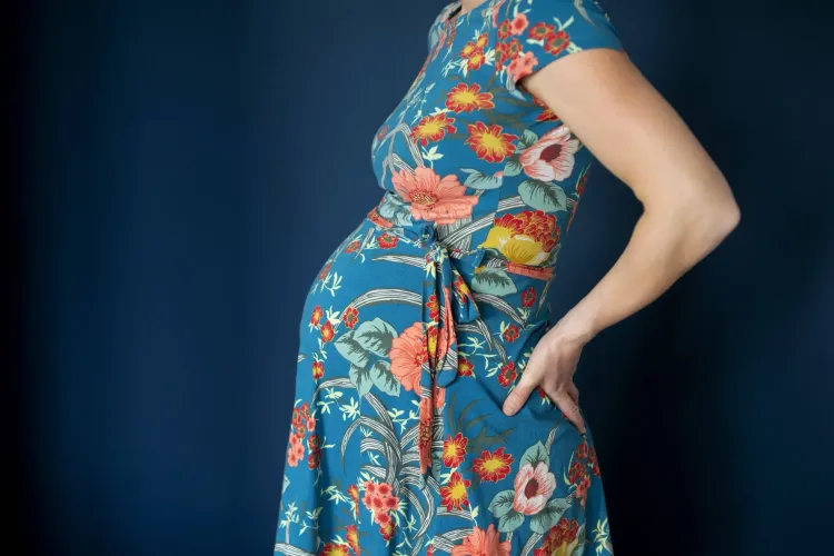 Bild einer schwangeren Frau in einem Kleid mit Blumenmuster