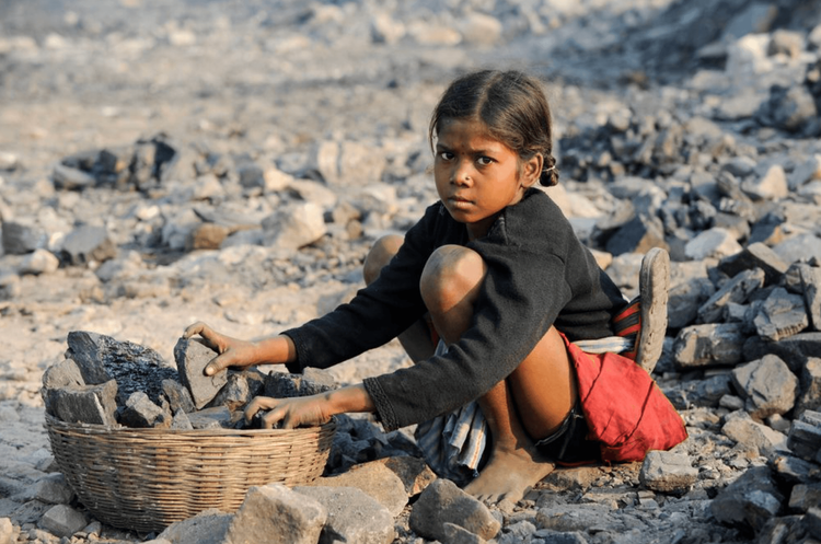 Ein Mädchen in Indien sammelt Kohle am Rande eines Kohletagebaus zum Verkauf auf dem Markt. 