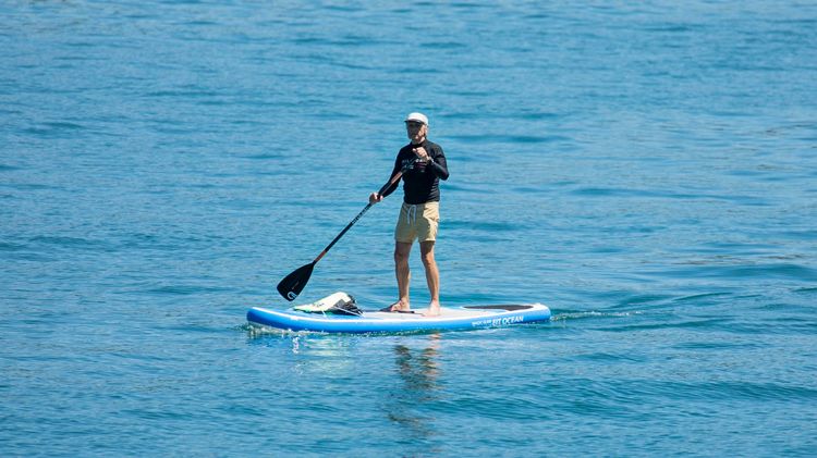 Ein älterer Mann betreibt Stand-Up Paddle einen modernen Sport auf dem Zürichsee.