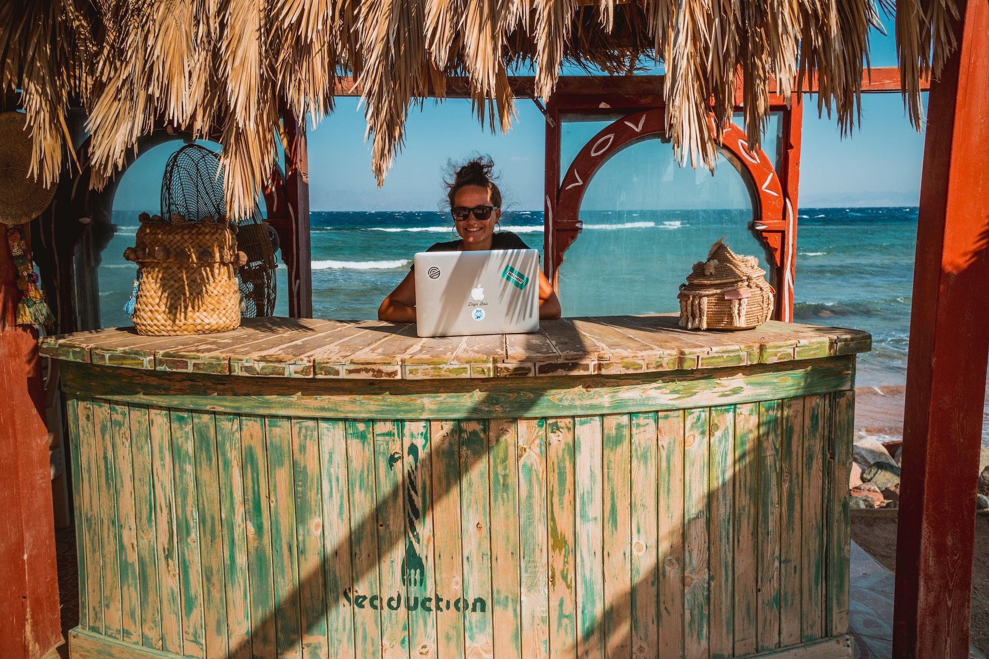 Frau mit Laptop an Strandbar